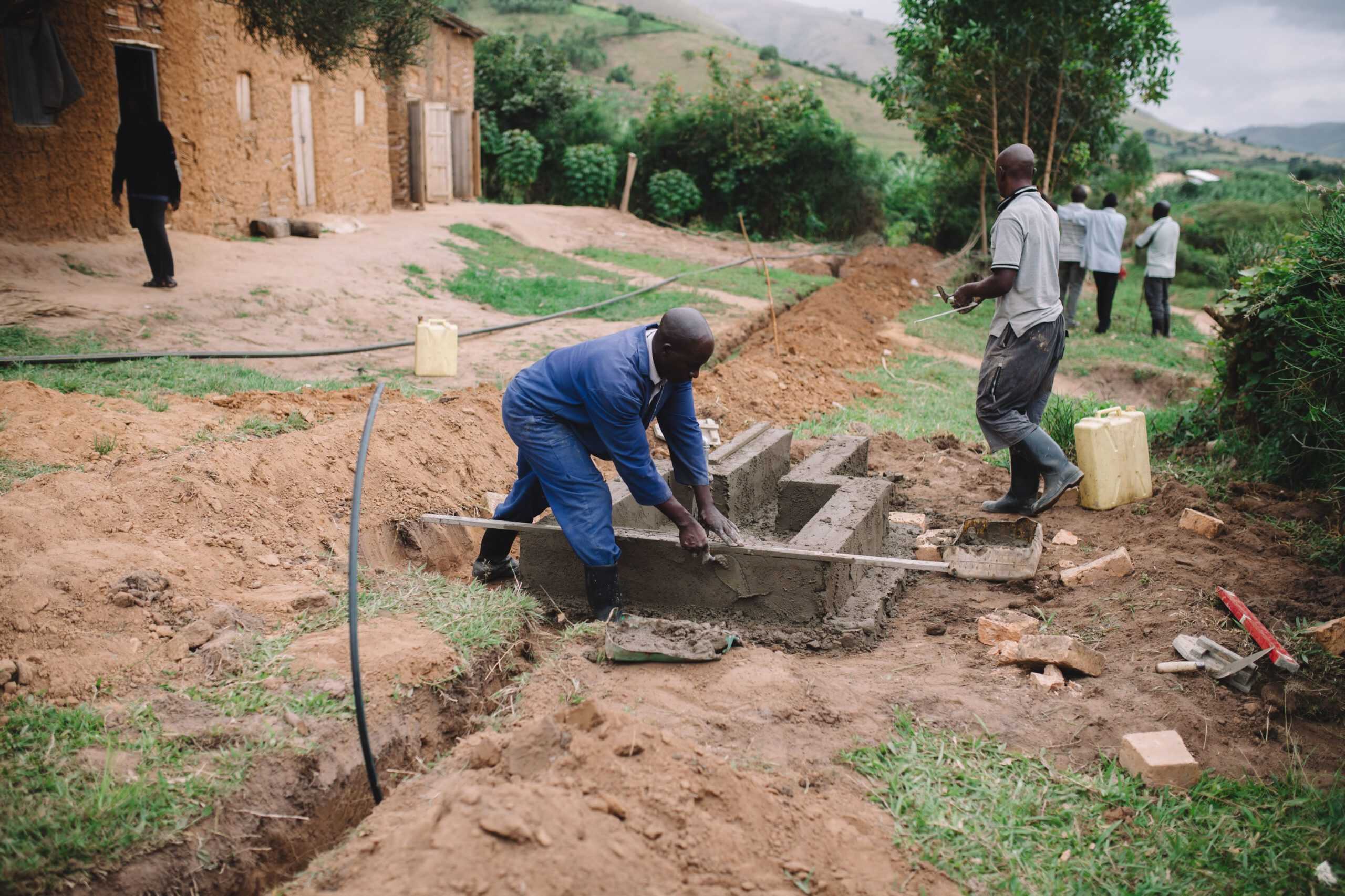 Ugandan labourers constructing a water tap stand